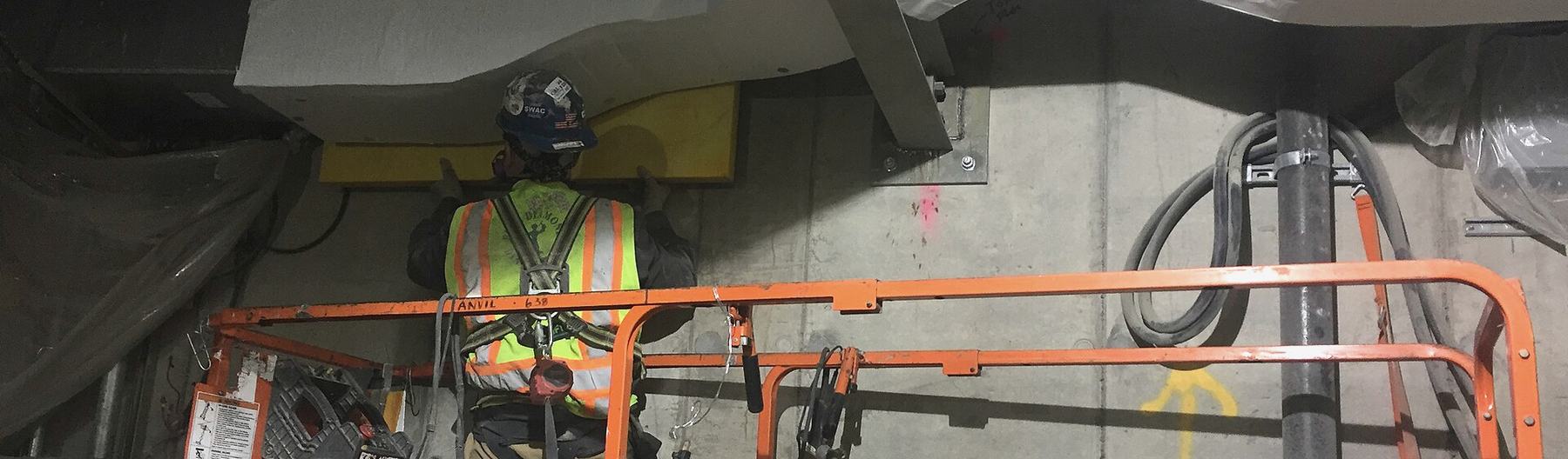 A worker on a lift finishing overhead mechanical work