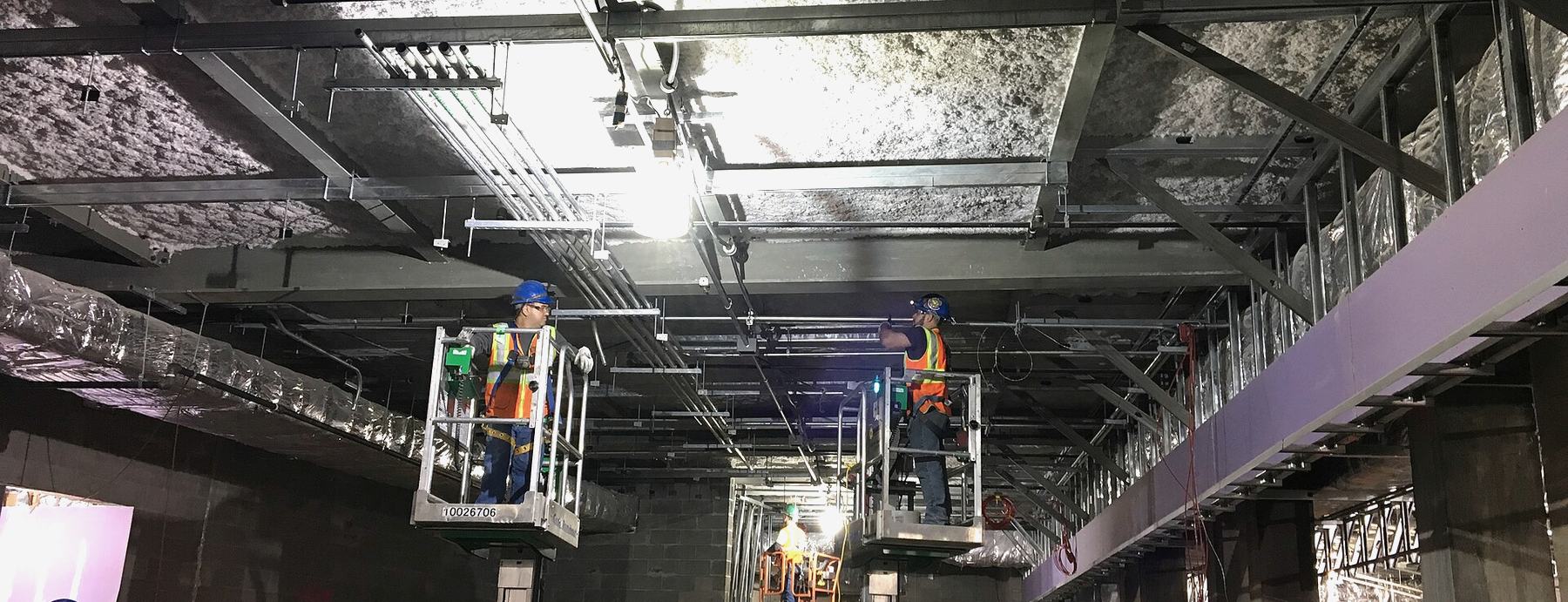 Two crews working overhead from lifts on an active construction site