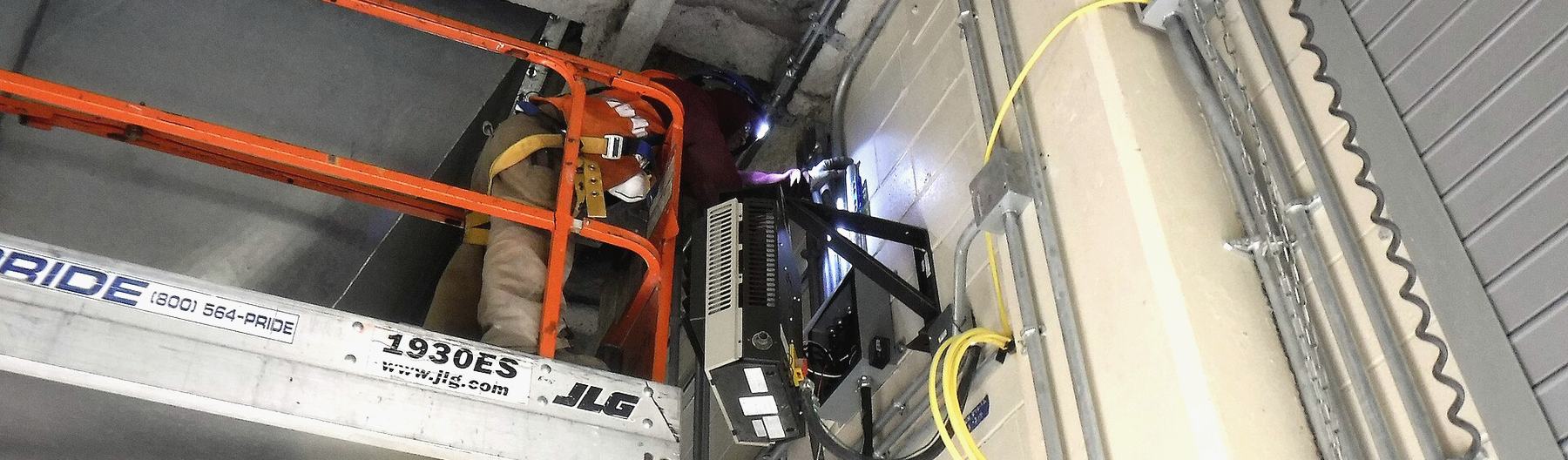 An electrician working from a lift installing conduit